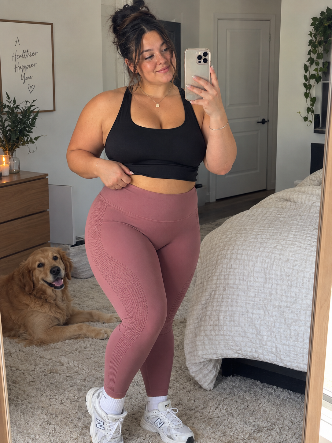 Customer in a black sports bra and dusty rose leggings at home